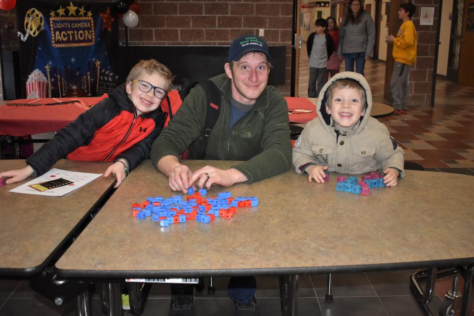 From left, Eddie Tervol, 7, a first grader at Addison Elementary School, dad Jason Tervol and Rhett Tervol, 3, smile for the camera while working on building word blocks during a literacy night event Tuesday at Addison Middle/High School. The program, held during March is Reading Month, was conducted by Adrian College elementary teacher education students.