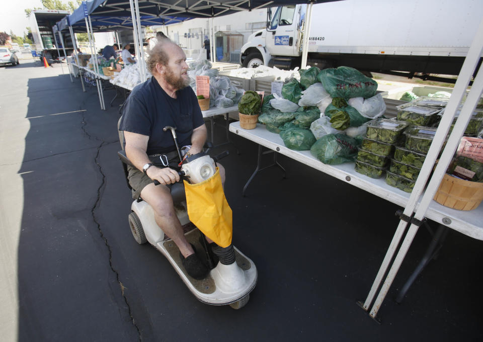 In this photo taken Wednesday, June 5, 2013, Carl Cupler looks over food items to be distributed at a Sacramento Food Bank event in Sacramento, Calif. The Sacramento Food Bank is one of the nations' first farm-to-fork food banks using local growers to provide healthier food to it's clients. Cupler is one of the thousands that "shop" at the farmers market style food distribution events.(AP Photo/Rich Pedroncelli)