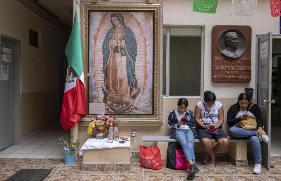 Migrants use their cell phones at the Casa del Migrante Catholic refugee shelter decorated with Our Lady of Guadalupe in Tijuana, Mexico, Tuesday, Sept. 26, 2023. While many places in Mexico provide shelter for migrants from other countries, some shelters in Tijuana have seen an influx of Mexicans fleeing violence, extortion and threats by organized crime. (AP Photo/Karen Castaneda)