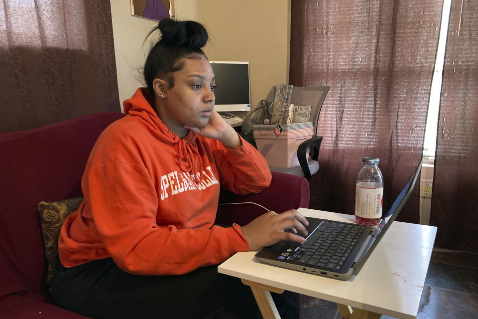 Kristen King, 17, a junior at Americus-Sumter High School, in Americus, Ga., sits on her living room couch, attending school via a Chromebook propped on a TV tray, in Americus, Ga., March 1, 2021. "It's been challenging," Kristen said. "I like hands-on help from my teachers. We can't really see our friends, like our school friends. We can't really socialize with them. We can't really do anything." (AP Photo/Jeff Amy)