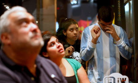 Supporters of Argentina's ruling party presidential candidate Daniel Scioli react as they watch Scioli's news conference televised in a bar near the campaign headquarters in Buenos Aires November 22, 2015. REUTERS/Martin Acosta