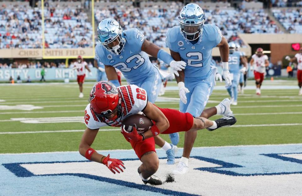 N.C. State wide receiver Terrell Timmons Jr. (82) pulls in a 28-yard touchdown reception as North Carolina linebacker Cedric Gray (33) and defensive back Don Chapman (2) defend during the first half of N.C. State’s game against UNC at Kenan Stadium in Chapel Hill, N.C., Friday, Nov. 25, 2022.