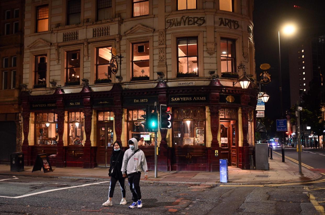 People wearing face masks walk past a quiet pub in the city centre of Manchester: AFP via Getty Images