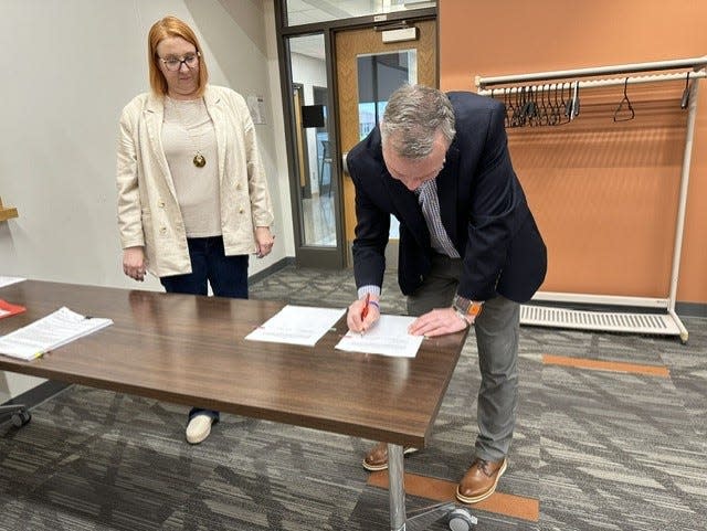 Incoming Ames CSD Superintendent Scott Grimes signs the district's superintendent contract.