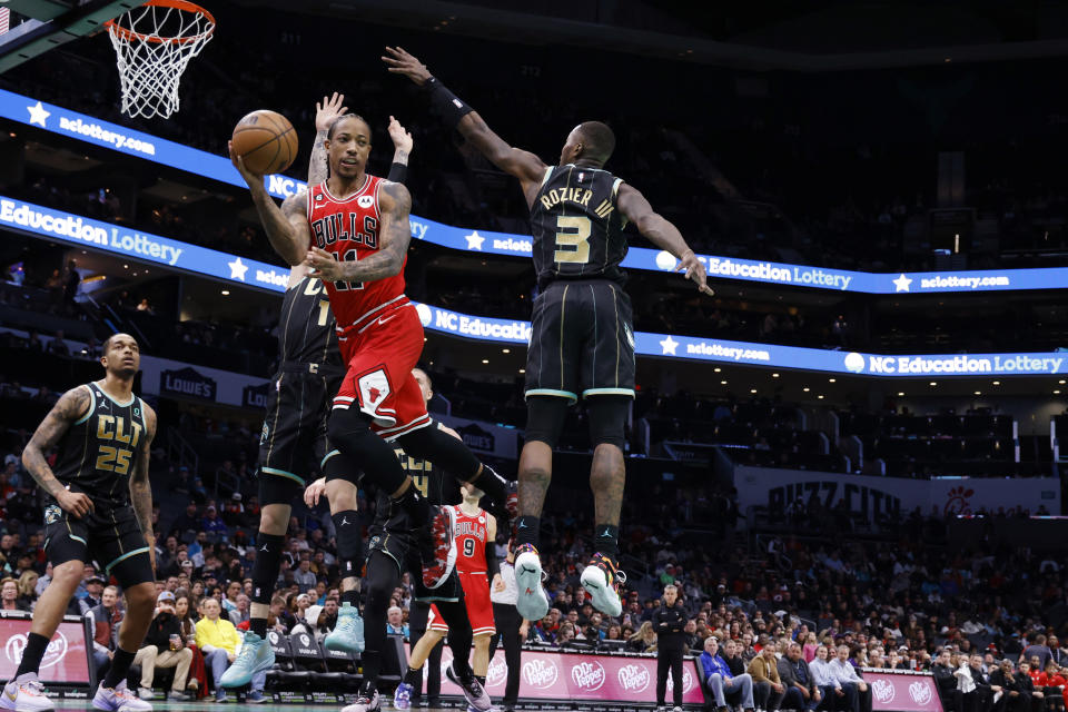 Chicago Bulls forward DeMar DeRozan (11) passes the ball around Charlotte Hornets guard Terry Rozier (3) as Hornets forward P.J. Washington (25) watches during the first half of an NBA basketball game in Charlotte, N.C., Thursday, Jan. 26, 2023. (AP Photo/Nell Redmond)