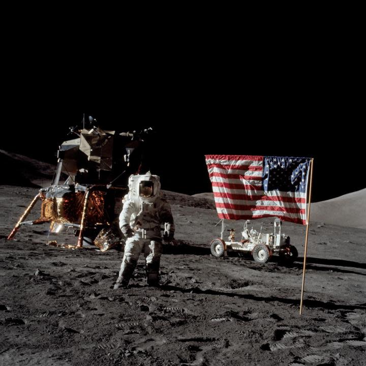 (13 Dec. 1972) — Astronaut Harrison H. Schmitt, Apollo 17 lunar module pilot, stands near the deployed United States flag on the lunar surface during extravehicular activity (EVA) of NASA’s final lunar landing mission in the Apollo series. The Lunar Module (LM) is at left background and the Lunar Roving Vehicle (LRV) at right background (partially obscured).