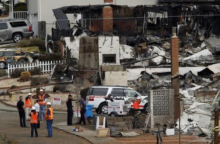 Investigators look over the remains of homes in a neighborhood that was destroyed when a natural gas pipeline ruptured and exploded, killing four people, and created a firestorm that destroyed 37 homes and injured more than 50 people last Thursday, in San Bruno, California September 13, 2010. REUTERS/Robert Galbraith