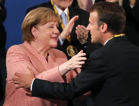 French President Emmanuel Macron is congratulated by German Chancellor Angela Merkel after being awarded the Charlemagne Prize during a ceremony in Aachen, Germany May 10, 2018. REUTERS/Wolfgang Rattay