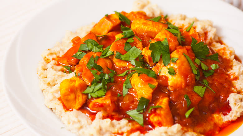 Meat and sauce on oatmeal in a white bowl