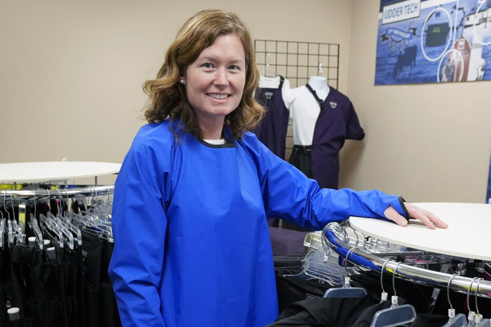 Ann Quigley poses Tuesday, Dec. 15, 2020, in a waterproof gown intended for milking cows made by Udder Tech Inc. a Rosemount, Minnesota-based dairy supply company. Minnesota bought 2,300 waterproof gowns intended for milking cows from Udder Tech Inc. The special gowns cost about $46 each when freight was included. (AP Photo/Jim Mone)