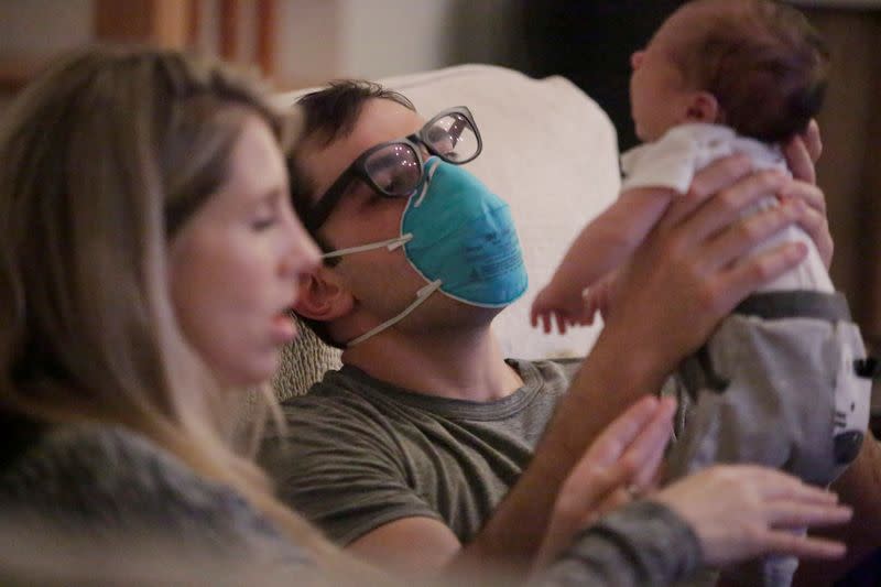 Emergency medicine physician Krajewski wears a mask as he holds his baby in New Orleans