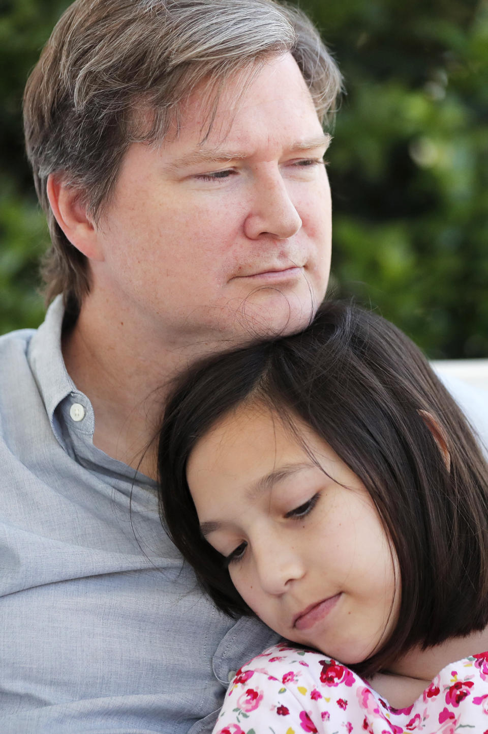 Juliet Daly, 12, sits with her father Sean Daly on the front porch of their family home in Covington, La., Thursday, April 30, 2020. A team of pediatric cardiology specialists found that Juliet had acute fulminant myocarditis (AFM), an uncommon heart condition that tends to present with sudden onset acute heart failure, cardiogenic shock or life-threatening arrhythmias. A nasal swab confirmed that Juliet was also COVID-19 positive and that she had a second viral infection – adenovirus. (AP Photo/Gerald Herbert)