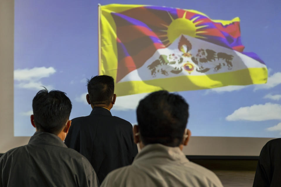 A video of the Tibetan flag is projected on a screen as the President of the Central Tibetan Administration Penpa Tsering, second left, stands up with other government officials for the Tibetan national anthem during a ceremony to mark the 86th birthday of their spiritual leader the Dalai Lama in Dharmsala, India, Tuesday, July 6, 2021. (AP Photo/Ashwini Bhatia)