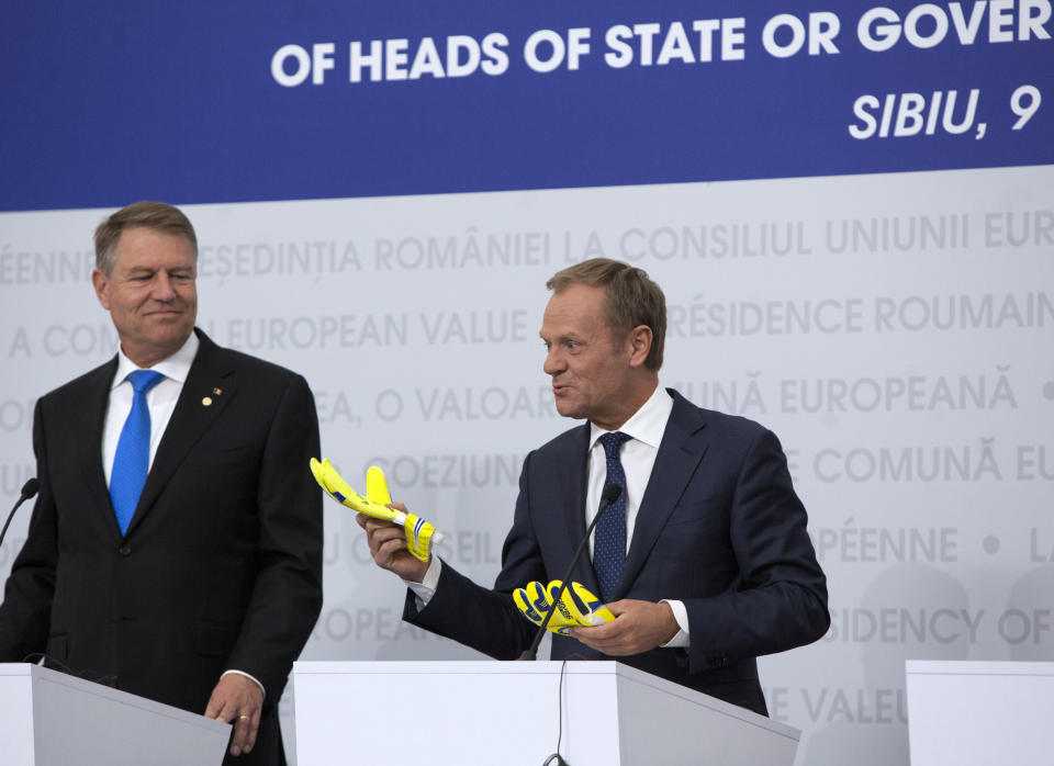 European Council President Donald Tusk, right, holds up a pair of mitts he received from retired Romanian soccer goalkeeper Helmuth Duckadam during a media conference at an EU summit in Sibiu, Romania, Thursday, May 9, 2019. The European Union will be holding an extra summit two days after the May 26 European elections to assess who should get three top jobs that will be vacated in the fall. (AP Photo/Virginia Mayo)