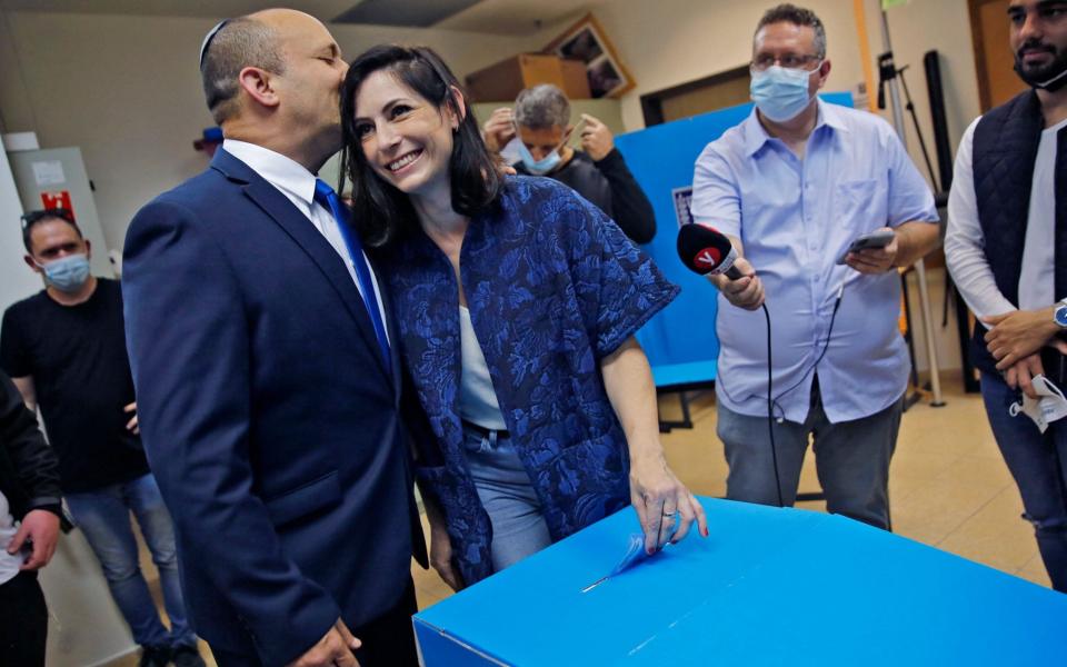 Bennett kisses his wife Gilat as she casts her vote at a polling station in the Israeli city of Raanana on March 23 - AFP