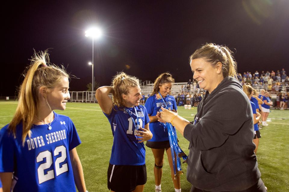 Dover-Sherborn athletic director Emily Sullivan hands out championship medals to Dover-Sherborn senior captain Kai Abbett (12) and sophomore Meredith Salvin (22) following the Raiders win in the Division 4 state championship game at Babson College in Wellesley, June 21, 2022. The Raiders beat the Manchester-Essex Hornets, 10-7.