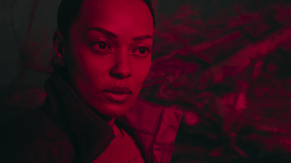 Saga Anderson bathed in red light in Alan Wake 2.