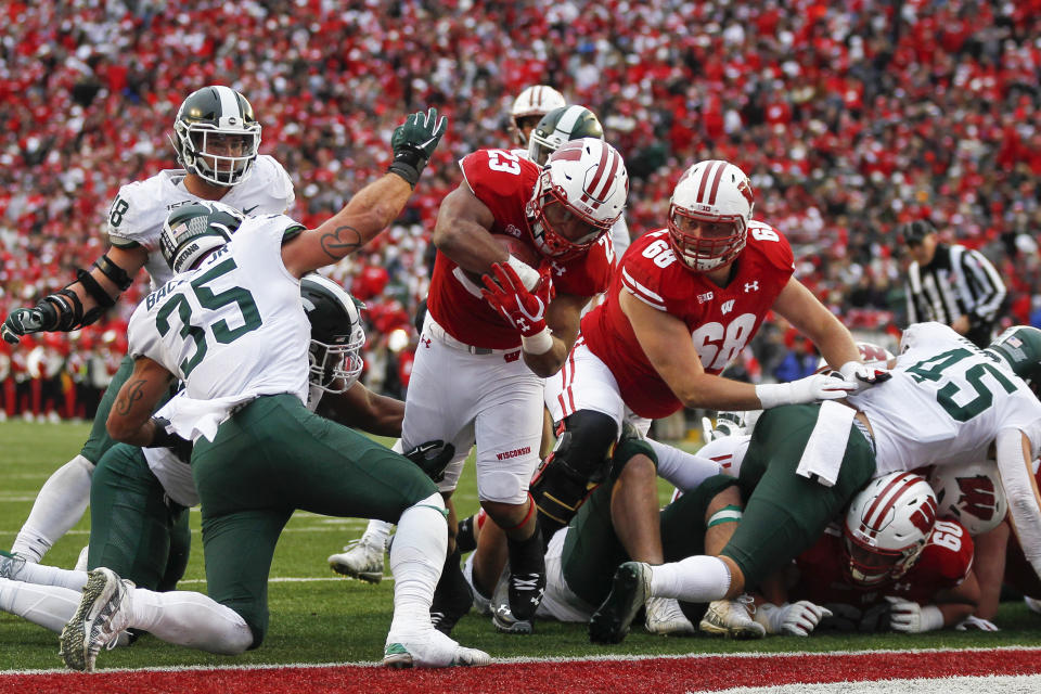 Wisconsin running back Jonathan Taylor (23) scores a touchdown against Michigan State linebacker Joe Bachie (35) during the second half of an NCAA college football game Saturday, Oct. 12, 2019, in Madison, Wis. Wisconsin won 38-0. (AP Photo/Andy Manis)