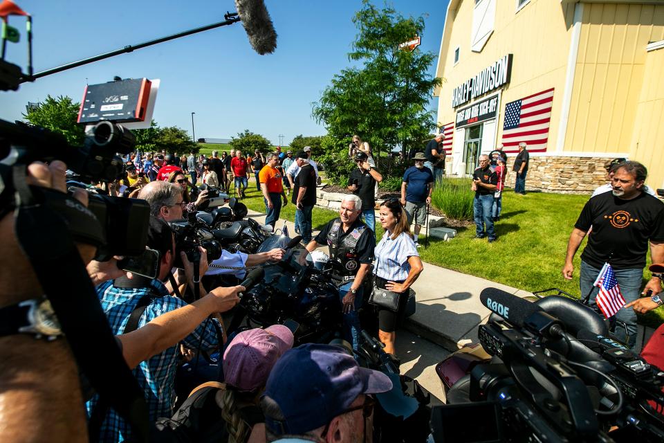 Former Vice President Mike Pence climbs onto his motorcycle while talking with his wife, Karen Pence, during the annual Roast and Ride fundraiser for U.S. Sen. Joni Ernst, Saturday, June 3, 2023, at Big Barn Harley-Davidson in Des Moines, Iowa.