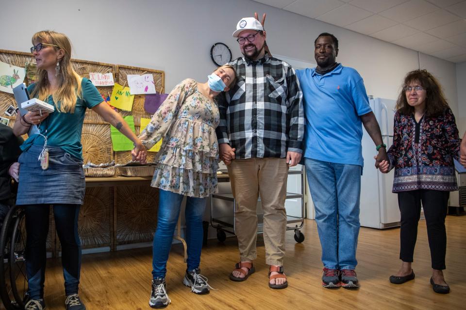 Christie Glenn leans into Dustin Mailman, associate pastor at Trinity Methodist in West Asheville, as Jeffery Glenn gives him bunny ears before while saying grace before eating dinner together on the final day of Code Purple, March 31, 2022.