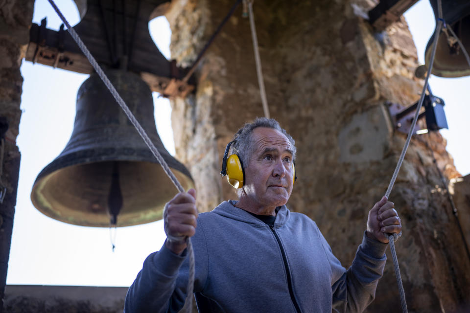 Xavier Masó, a student of the Vall d'en Bas School of Bell Ringers, performs playing two bronze bells at the church bell tower of the12th-century Sant Romà church, at the tiny village of Joanetes, about two hours north of Barcelona, Spain, Saturday, July 29, 2024. A school set up to revive the manual ringing of church bells has graduated its first class of 18 students after learning their ringing skills. (AP Photo/Emilio Morenatti)