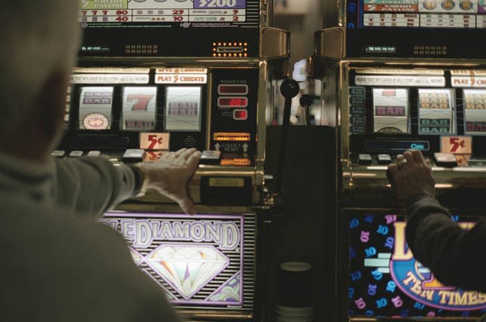 Two people playing slot machines with one labeled "Double Diamond" and the other labeled "Lion Ten Times Pay."