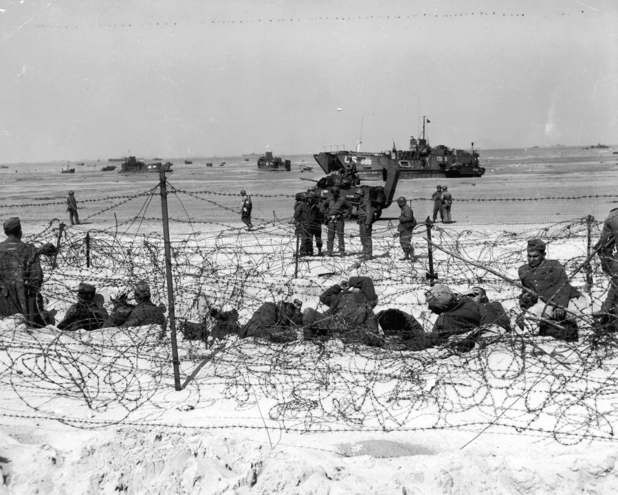 6th June 1944:  German prisoners of war are detained behind barbed wire by American soldiers on Utah Beach on the coast of France, World War II.  (Photo by Hulton Archive/Getty Images)