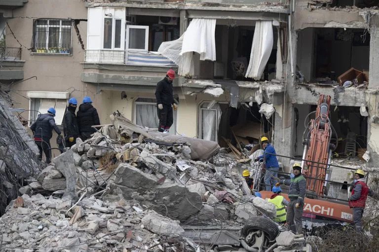 Rescatistas y bomberos buscan sobreviventes entre los escombros de un edificio en Antakya, Turquía