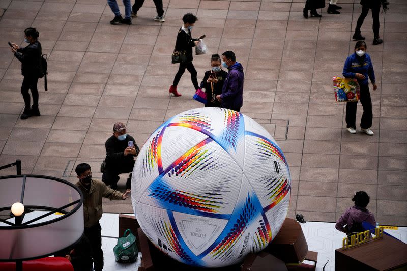 Personas utilizando mascarillas miran el modelo gigante del balón de la Copa Mundial de la FIFA Qatar 2022, en medio del brote de la enfermedad coronavirus (COVID-19) en Shanghái, China