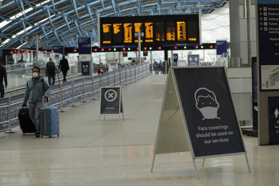 A sign recommending people wear face coverings to help stop the spread of coronavirus is displayed in Waterloo station, London, Thursday, June 4, 2020. Waterloo station, which is wide recognised as the busiest train station in Britain, is still much quieter than normal as most commuters are working from home and not commuting into central London offices. (AP Photo/Matt Dunham)