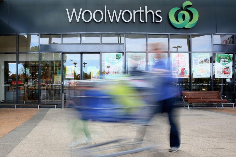 Woolworths shopper (motion blurred) exits supermarket with full shopping trolley