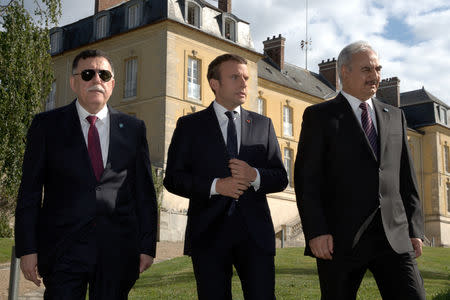 French President Emmanuel Macron walks with Libyan Prime Minister Fayez al-Sarraj (L), and General Khalifa Haftar (R), commander in the Libyan National Army (LNA), after talks over a political deal to help end Libya’s crisis in La Celle-Saint-Cloud near Paris, France, July 25, 2017. REUTERS/Philippe Wojazer/Files