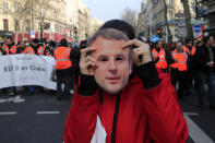 A protester hods a mask of French President Emmanuel Macron during a demonstration, Friday, Jan. 24, 2020 in Paris. French unions are holding last-ditch strikes and protests around the country Friday as the government unveils a divisive bill redesigning the national retirement system. (AP Photo/Michel Euler)