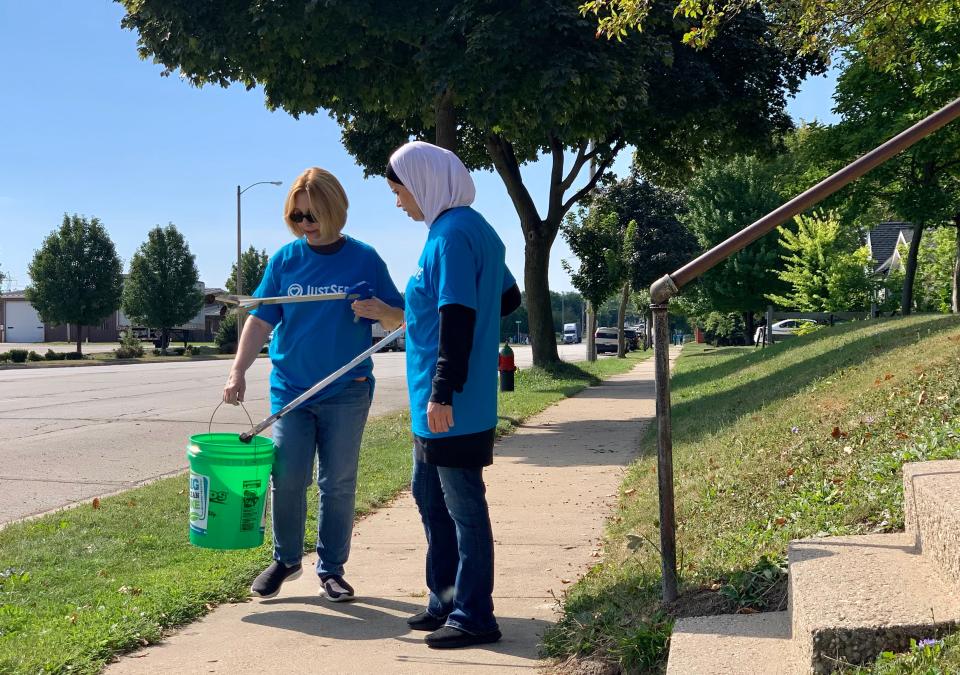 Sheri Bohl, a member of the Church of Jesus Christ of Latter-day Saints, left, and Muna Mousa, a member of the Islamic Society of Milwaukee, pick up trash during the second annual Interfaith Neighborhood Clean-up on Saturday.