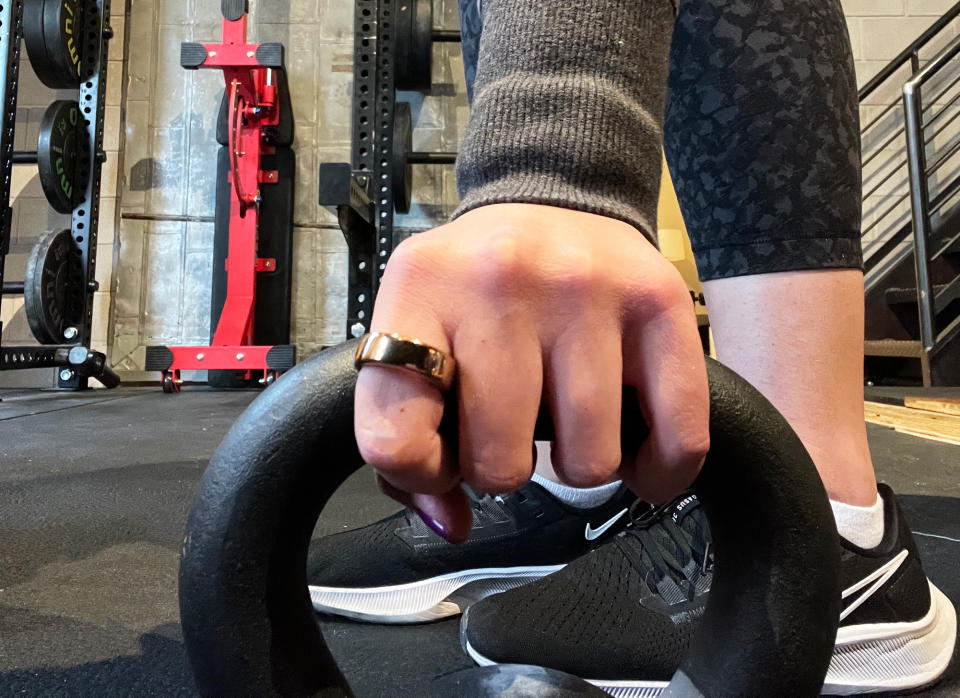 An original photo from Spy senior commerce editor of the oura ring being worn while grasping a kettlebell in a gym