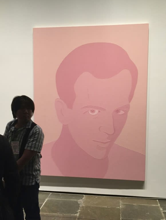 A patron stands next to "Peach Oswald" (2001) by Wayne Gonzales