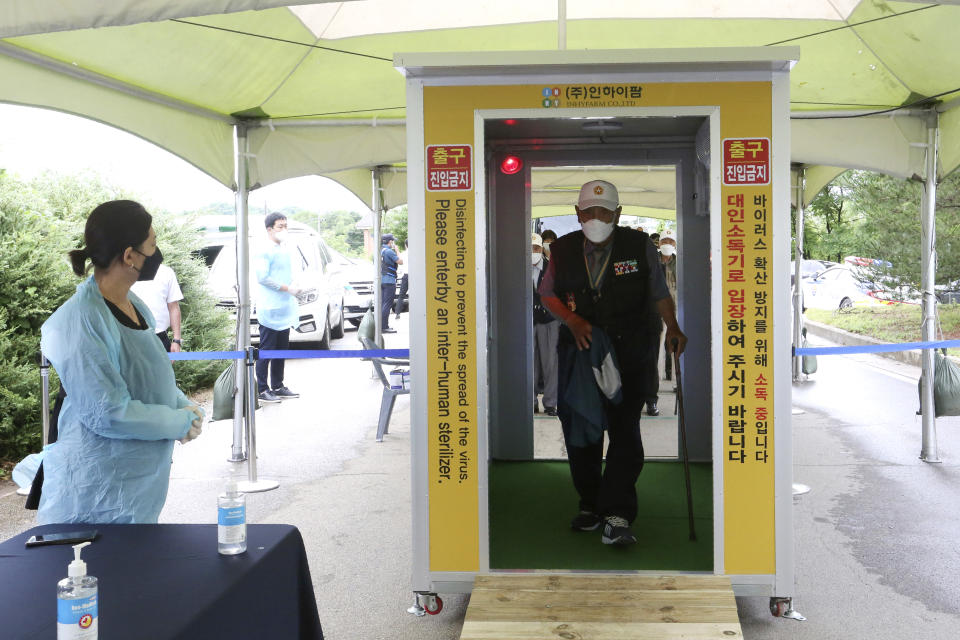 A Koran War veteran walks through a sterilizer as a precaution against the new coronavirus while he arrives to attend a ceremony to mark the 70th anniversary of the outbreak of the Korean War in Cheorwon, near the border with North Korea, South Korea, Thursday, June 25, 2020. (AP Photo/Ahn Young-joon)