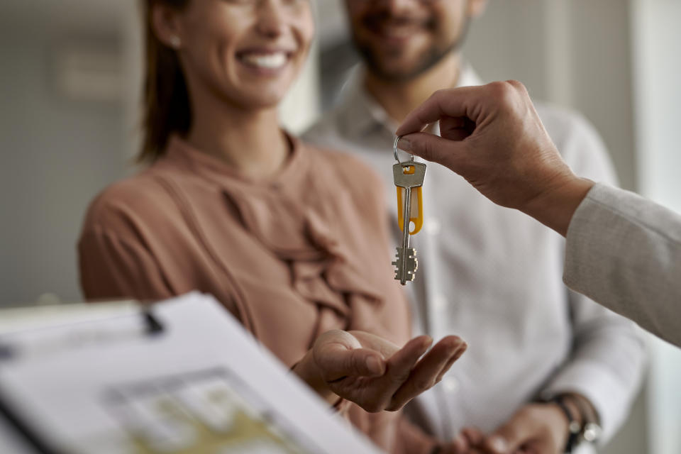 Close-up of real estate agent giving new house keys to a couple.