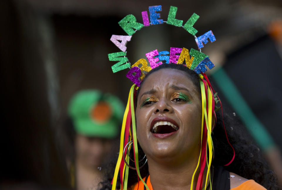 A woman wears a crown with the words "Marielle present," in honor of slain councilwoman Marielle Franco, during the "Se Benze que da" block party which she created in 2005, in the Mare slum of Rio de Janeiro, Brazil, Saturday, Feb. 23, 2019. Merrymakers take to the streets in hundreds of open-air "bloco" parties ahead of Rio's over-the-top Carnival, the highlight of the year for many. (AP Photo/Silvia Izquierdo)