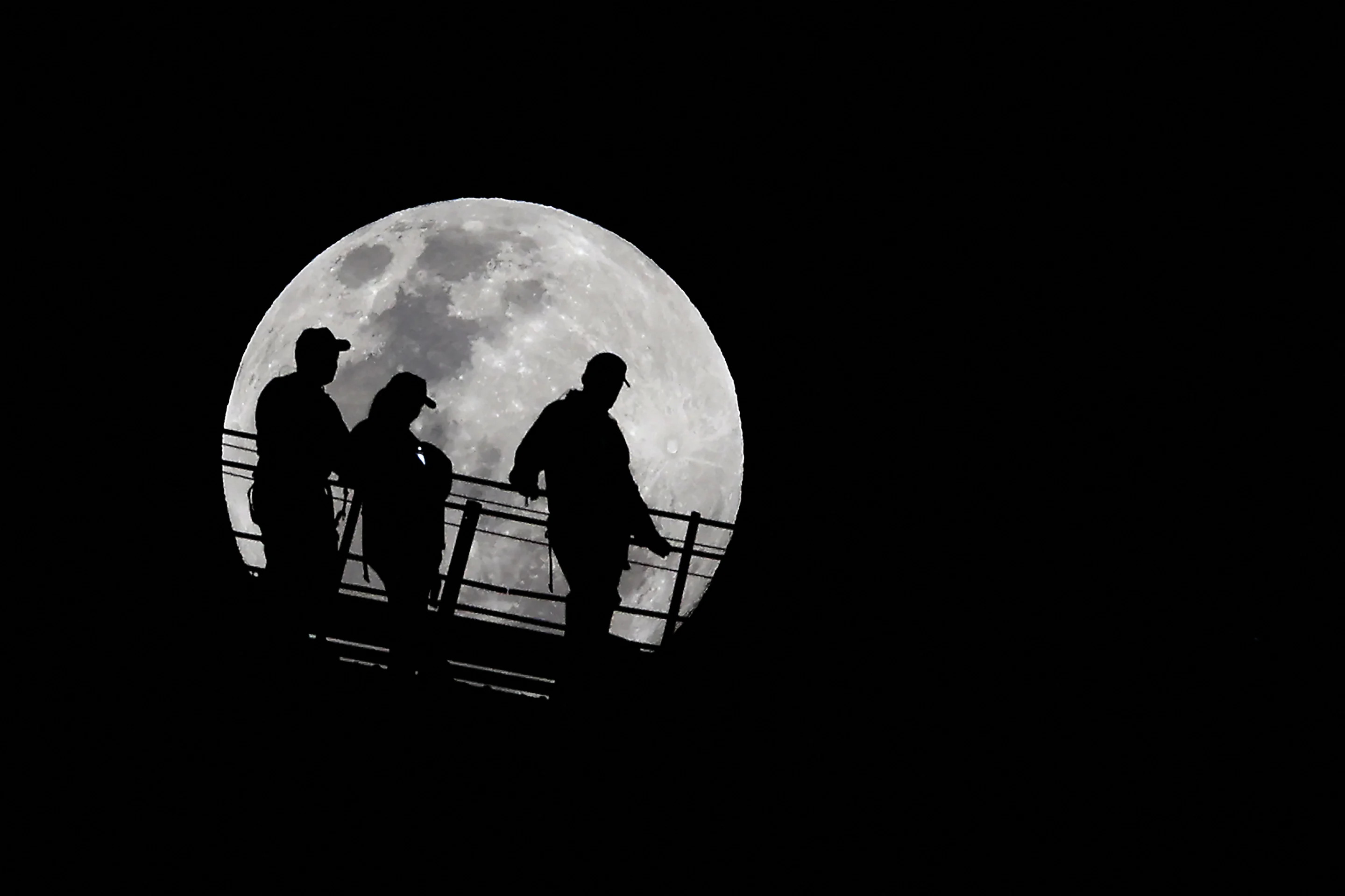 Climbers are silhouetted against the full moon near the summit of the Sydney Harbour Bridge in Australia on Tuesday.