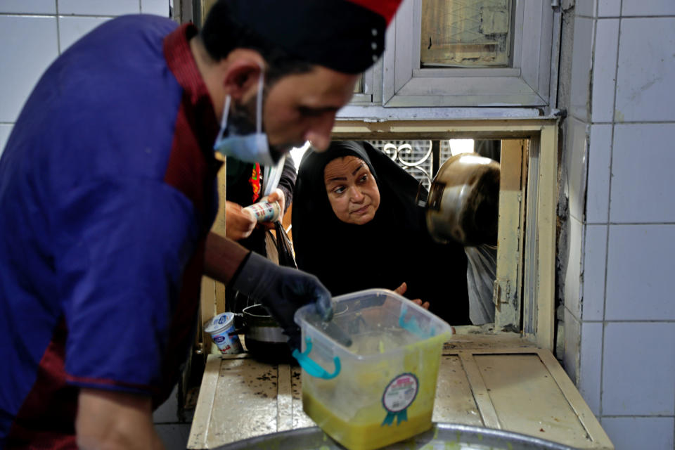 People receive free food being distributed ahead of Iftar, the evening meal breaking the Ramadan fast, at the Abdul-Qadir al-Gailani mosque in Baghdad, Iraq, Tuesday, May 11, 2021. Muslims throughout the world are marking the last days of Ramadan -- a month of fasting during which observants abstain from food, drink and other pleasures from sunrise to sunset. (AP Photo/Khalid Mohammed)