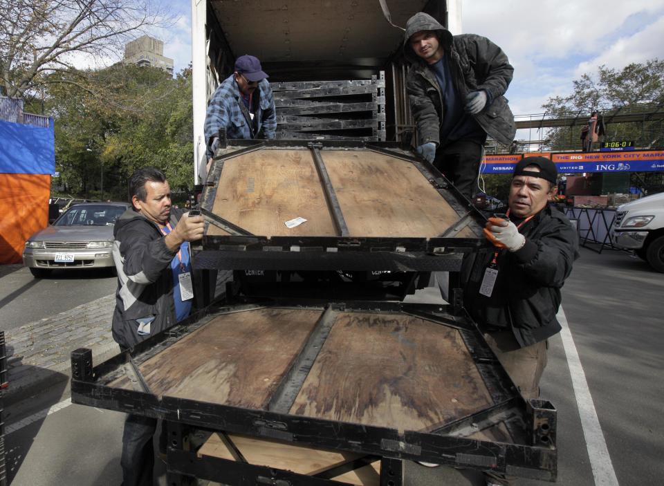 Workers unload sections of a stage near the New York City Marathon finish line, in New York's Central Park, Friday, Nov. 2, 2012. The course for Sunday's New York City Marathon will be the same since there was little damage but getting to the finish line could still be an adventure for runners from outlying areas. Such is life in Sandy's aftermath disrupted trains, planes, buses and ferries, flooded buildings, blocked roads and knocked out power. (AP Photo/Richard Drew)