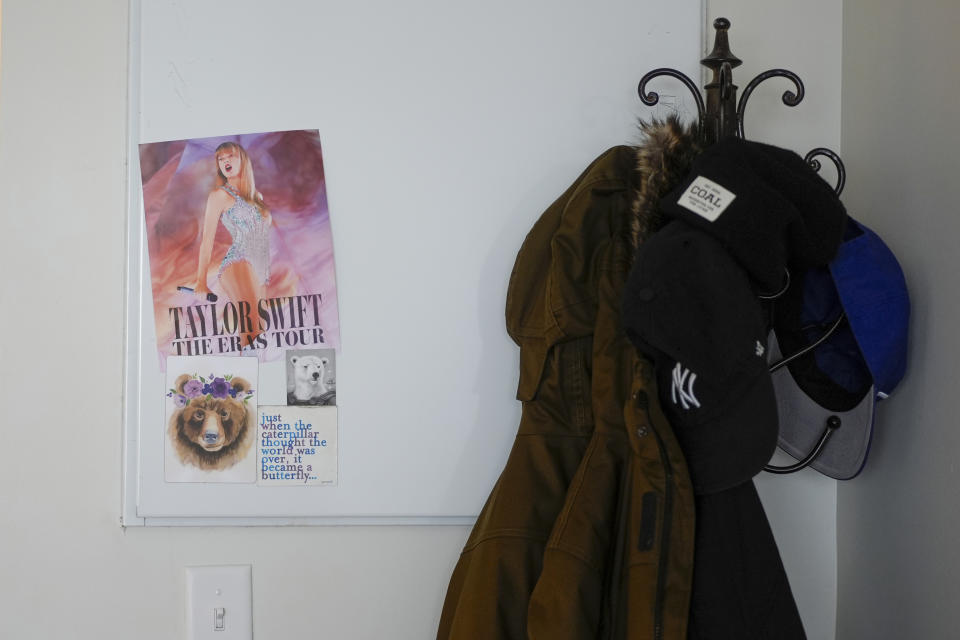 A poster of Taylor Swift and a smaller sign that reads, "just when the caterpillar thought the world was over, it became a butterfly…." Next to the coat rack in Ashton Colby's apartment in Columbus, Ohio, on Thursday, Jan. 18, 2024. Ohio Gov. Mike DeWine announced proposals this month that transgender advocates say could block access to gender-affirming care provided by independent clinics and general practitioners, leaving thousands of adults scrambling for treatment and facing health risks. Colby, 31, fears the clinic where he gets the testosterone he has taken since age 19 would no longer offer it. (AP Photo/Carolyn Kaster)