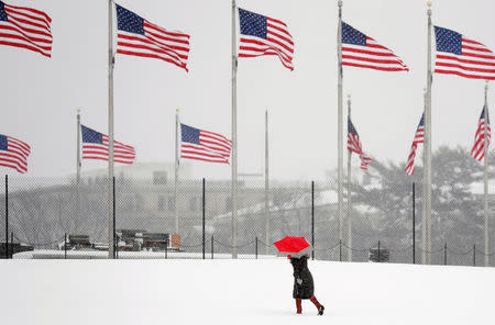 A woman holds an umbrella as she walks toward the Washington Monument during a snowstorm in Washington, U.S., March 21, 2018. REUTERS/Kevin Lamarque