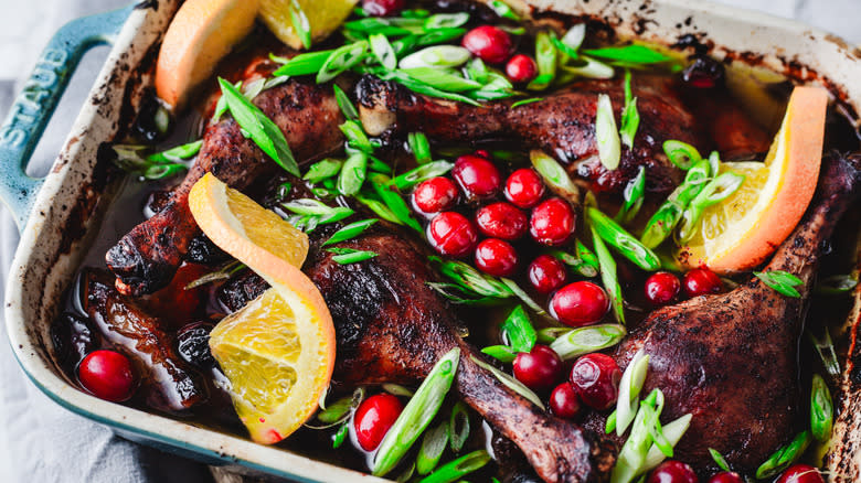 Duck legs, cranberries and orange in casserole dish