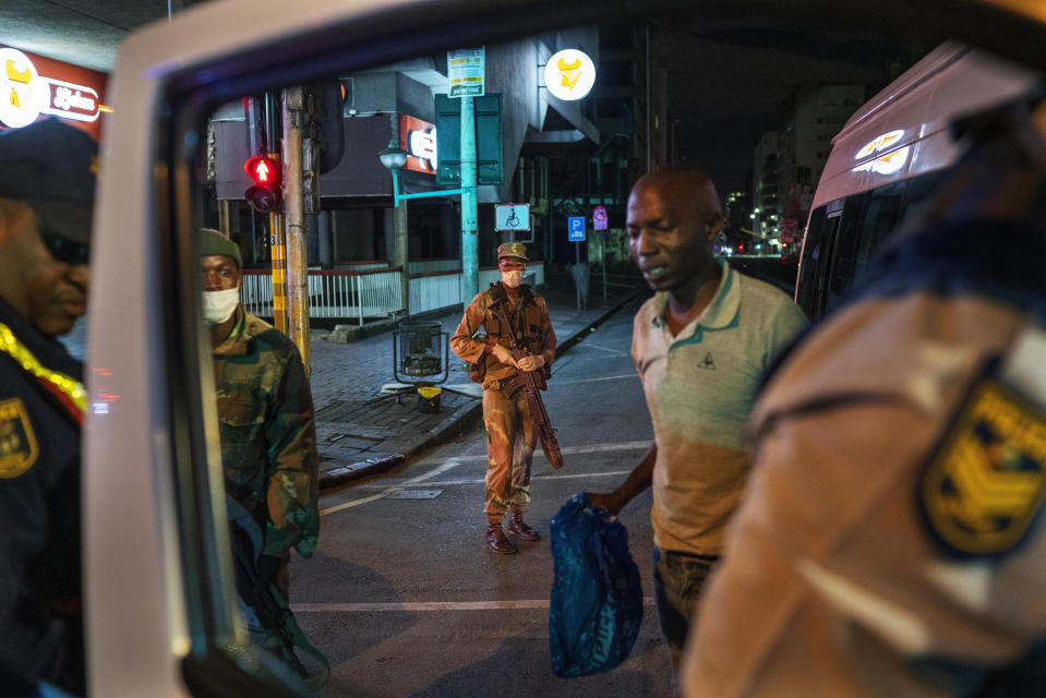South African Defense Forces and police check a minibus driver who violated the lockdown downtown Johannesburg, South Africa, Friday, March 27, 2020. Police and army started patrolling moments after South Africa went into a nationwide lockdown for three weeks in an effort to mitigate the spread to the coronavirus. The new coronavirus causes mild or moderate symptoms for most people, but for some, especially older adults and people with existing health problems, it can cause more severe illness or death.(AP Photo/Jerome Delay)