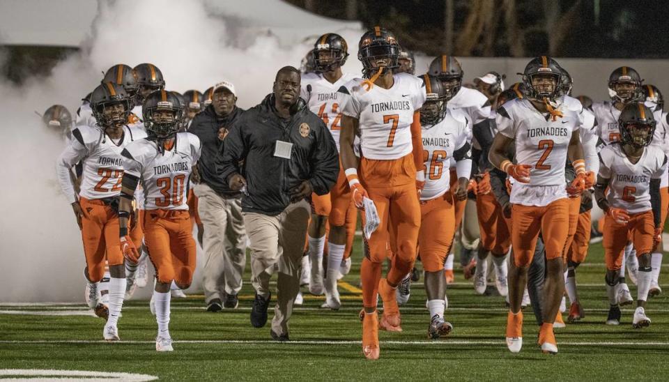 Associate Head Coach Ben Hanks runs onto the field with players to start the game as Booker T. Washington Tornadoes play the Bolles Bulldogs for Class 4A FHSAA State Championship Title at Daytona Stadium in Daytona Beach on Wednesday, December 11, 2019.