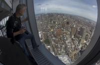 A news photographer looks out the window at the Manhattan skyline from the One World Observatory observation deck on the 100th floor of the One World Trade center tower in New York during a press tour of the site May 20, 2015. One World Observatory will open to the public on May 29. (REUTERS/Mike Segar)