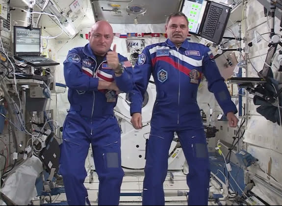NASA astronaut Scott Kelly (left) gives a thumb's up sign while floating next to fellow one-year crewmate Mikhail Kornienko of Russia on the International Space Station after a video chat with NASA chief Charles Bolden and others on March 30, 2