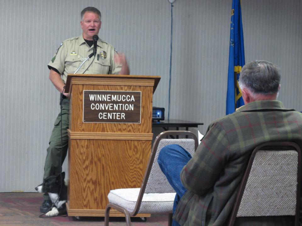 Humboldt County Sherriff's Sgt. Chris Aker describes the county's drug interdiction program on U.S. Interstate 80 in Winnemucca, Nev., Tuesday, March 11, 2014, as his K-9 ``Boots'' peers out from behind the podium during a public meeting at the Winnemucca Convention Center. About 40 people attended as Sheriff Ed Kilgore and others helped respond to questions about two federal lawsuits recently filed accusing county deputies of seizing tens of thousands of dollars without bringing criminal charges against suspected drug traffickers. (AP Photo/Scott Sonner)